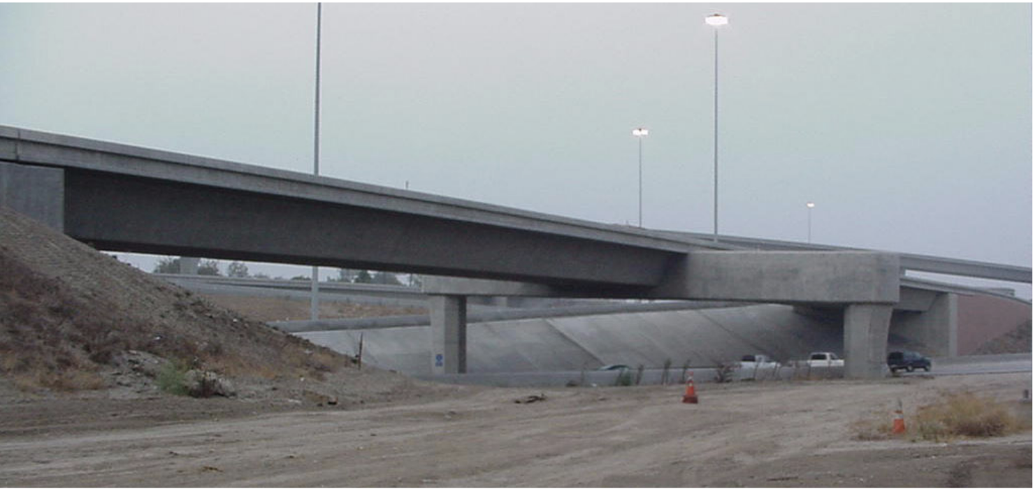 Figure A. View of 91/5 overcrossing located in Orange County in southern California. The deck is supported at mid-span by an outrigger prestressed beam, while at each abutment it rests on four elastomeric pads and is attached with four fluid dampers.